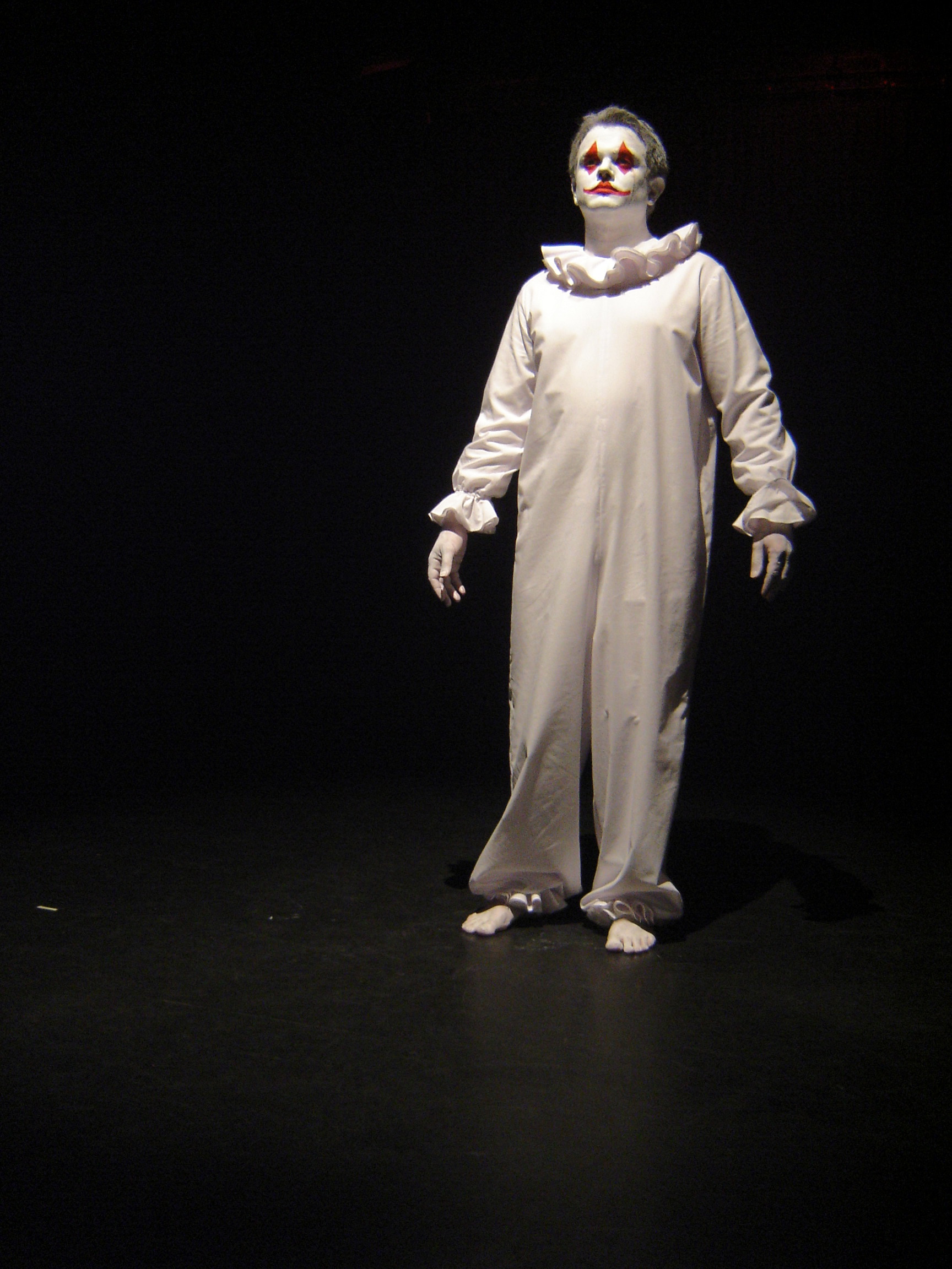 William Pollard performing in a white Pierrot costume under stage lighting